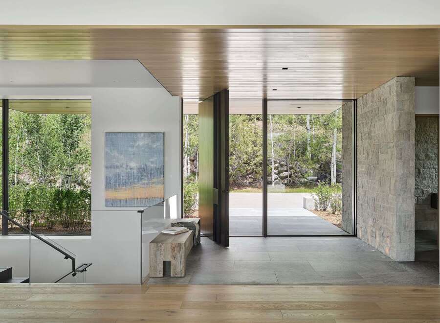 Experience seamless indoor-outdoor living in this stunning entryway, featuring expansive glass doors that open to a lush natural landscape.