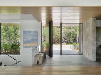Experience seamless indoor-outdoor living in this stunning entryway, featuring expansive glass doors that open to a lush natural landscape.