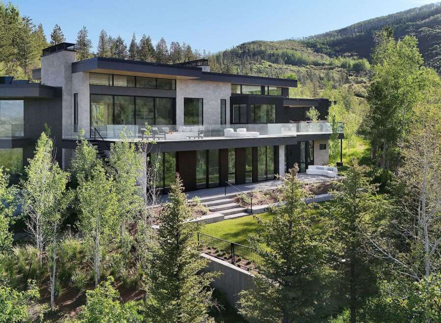 Experience modern luxury in this stunning mountain home, featuring expansive glass walls and sleek architectural lines that blend seamlessly with the natural landscape.