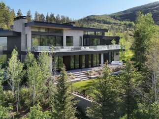 Experience modern luxury in this stunning mountain home, featuring expansive glass walls and sleek architectural lines that blend seamlessly with the natural landscape.