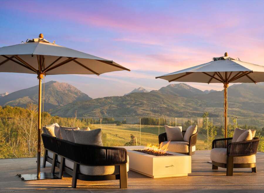 Experience breathtaking mountain views from this luxurious outdoor living space, complete with a modern fire pit and comfortable seating.