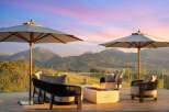 Experience breathtaking mountain views from this luxurious outdoor living space, complete with a modern fire pit and comfortable seating.