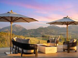 Experience breathtaking mountain views from this luxurious outdoor living space, complete with a modern fire pit and comfortable seating.