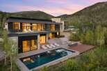 Experience luxury mountain living in this stunning modern home, featuring a sleek design with expansive glass walls and stone accents.