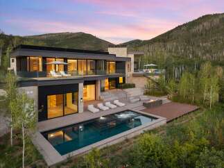 Experience luxury mountain living in this stunning modern home, featuring a sleek design with expansive glass walls and stone accents.