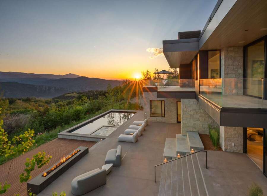 Experience luxury living with this stunning modern home featuring a sleek infinity pool and a linear gas fireplace, perfect for enjoying breathtaking sunset views over the mountains.