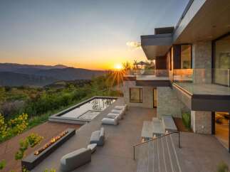 Experience luxury living with this stunning modern home featuring a sleek infinity pool and a linear gas fireplace, perfect for enjoying breathtaking sunset views over the mountains.