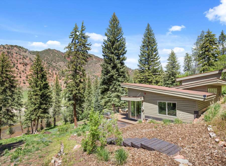 Experience modern living nestled in nature with this stunning home featuring a unique architectural design and expansive deck overlooking a serene river.