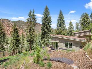 Experience modern living nestled in nature with this stunning home featuring a unique architectural design and expansive deck overlooking a serene river.