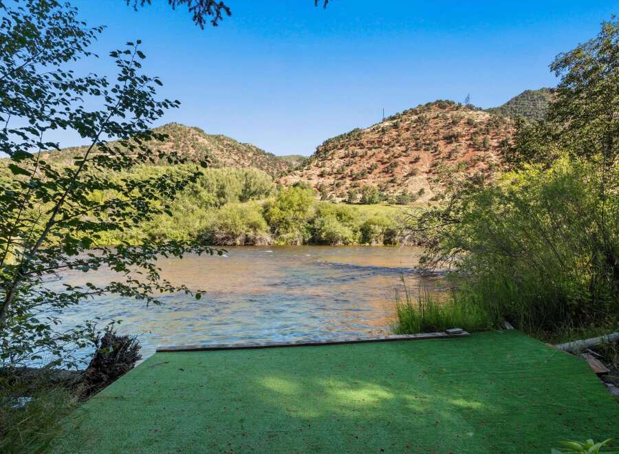 Experience serene riverfront living with this stunning property, featuring a lush green lawn leading directly to the water's edge.