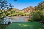 Experience serene riverfront living with this stunning property, featuring a lush green lawn leading directly to the water's edge.