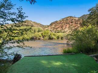 Experience serene riverfront living with this stunning property, featuring a lush green lawn leading directly to the water's edge.