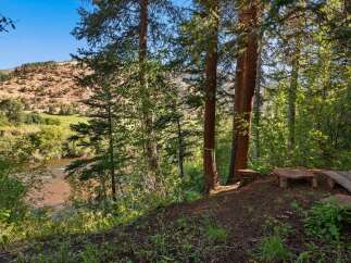 Escape to this serene mountain retreat, offering breathtaking views of a winding river and rugged red rock formations.