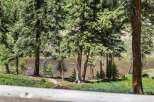 Experience serene living with this stunning property featuring a tranquil riverfront setting surrounded by lush evergreen trees.