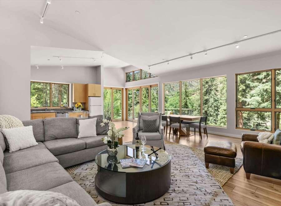 Experience luxurious living in this stunning open-concept great room, featuring a spacious sectional sofa, a modern glass coffee table, and a dining area with a view.