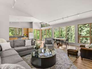 Experience luxurious living in this stunning open-concept great room, featuring a spacious sectional sofa, a modern glass coffee table, and a dining area with a view.