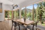 Experience breathtaking mountain and river views from this stunning dining area, featuring expansive windows and a modern wooden table.