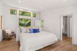Experience serene living in this beautifully appointed bedroom, featuring large windows that offer stunning views of the lush greenery outside.
