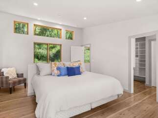 Experience serene living in this beautifully appointed bedroom, featuring large windows that offer stunning views of the lush greenery outside.