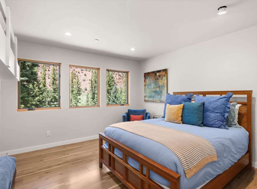 Experience breathtaking mountain views from this serene bedroom, featuring three large windows that flood the space with natural light.
