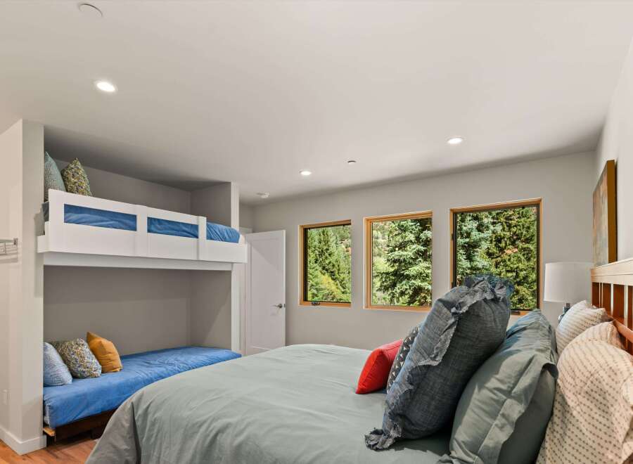 This bedroom offers a unique sleeping arrangement with a built-in bunk bed and a lower daybed, perfect for families or guests.