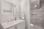 This modern bathroom features a sleek white vanity with a double sink and chrome fixtures, complemented by a large framed mirror.