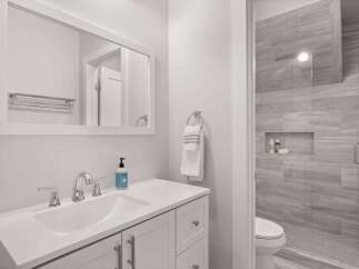 This modern bathroom features a sleek white vanity with a double sink and chrome fixtures, complemented by a large framed mirror.