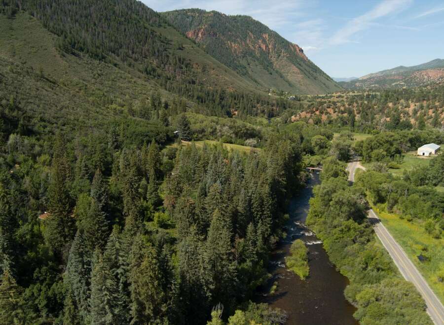 Discover this stunning property nestled in a picturesque mountain valley, offering a serene retreat with a flowing river and lush green forests.