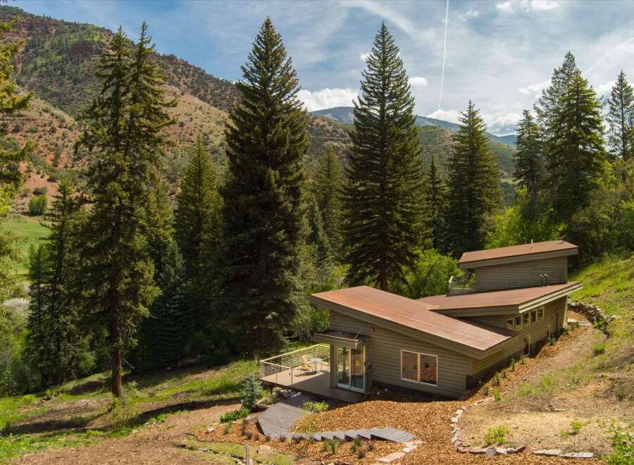 Nestled amidst a lush forest and rolling hills, this modern home offers a serene retreat.