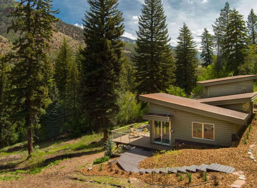 Nestled amidst towering evergreen trees and rolling hills, this modern home offers a serene mountain retreat.