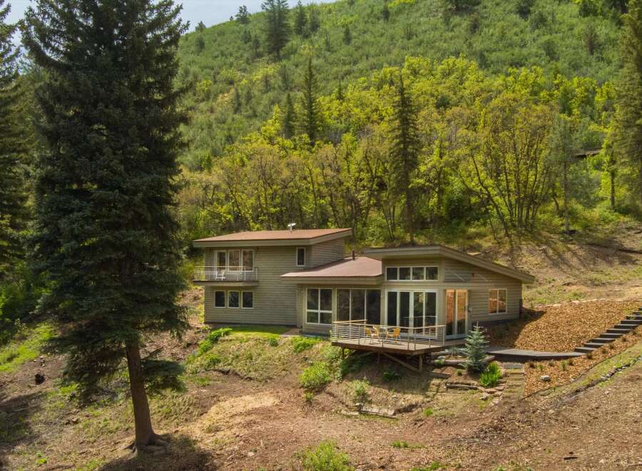 Nestled amidst lush greenery, this modern home offers a serene retreat with its expansive windows and multiple balconies overlooking the natural landscape.