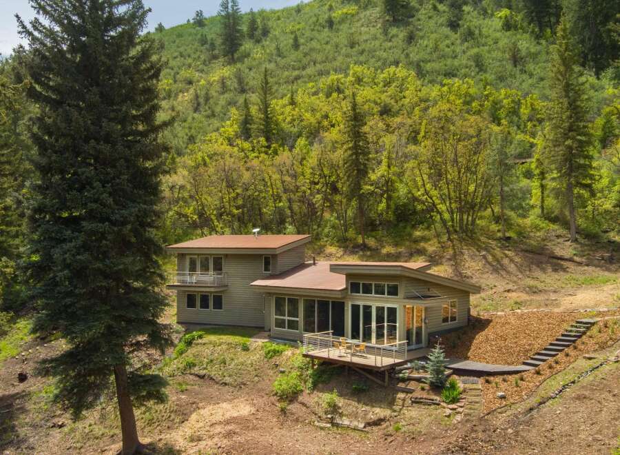 Nestled amidst a lush green hillside, this modern home offers a serene retreat with stunning natural surroundings.