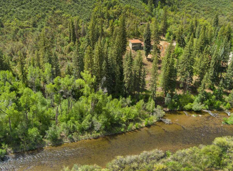 Nestled amidst a lush forest, this property offers a serene escape with a charming house overlooking a tranquil river.