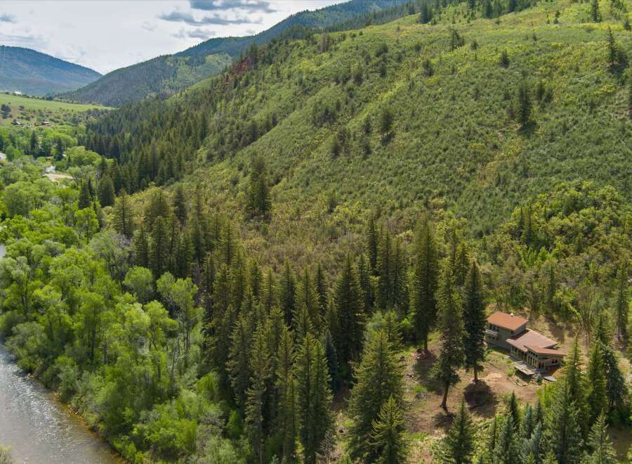 Nestled amidst a lush forest, this stunning property offers a serene retreat with a modern home featuring expansive windows and multiple decks.