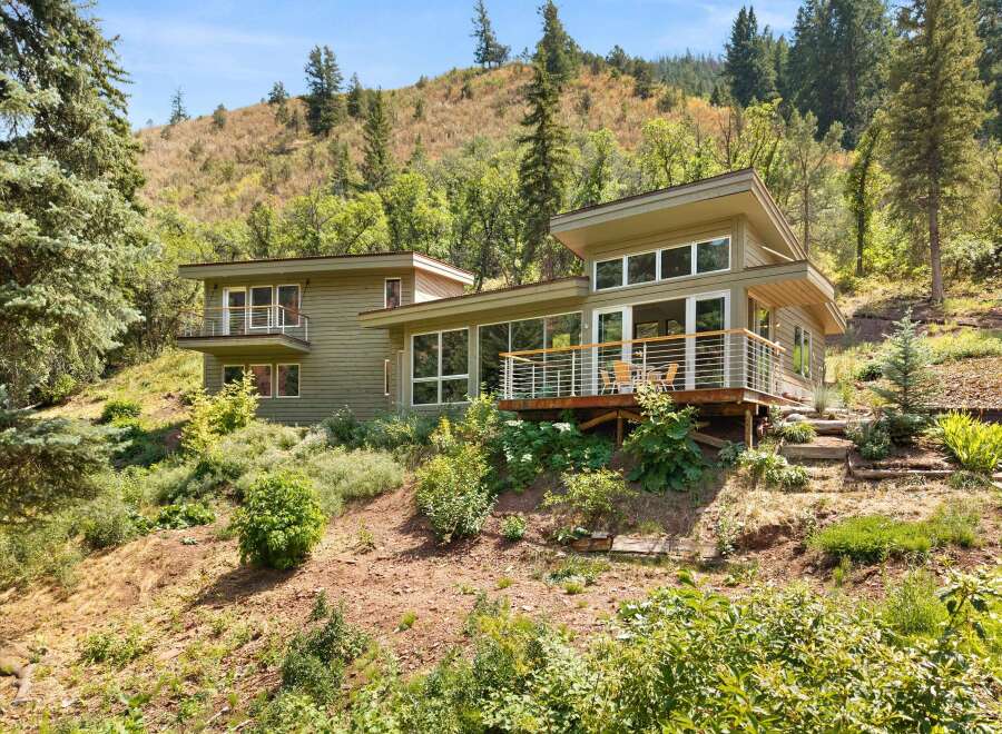 Nestled into a hillside, this modern home offers stunning natural views and a seamless indoor-outdoor living experience.