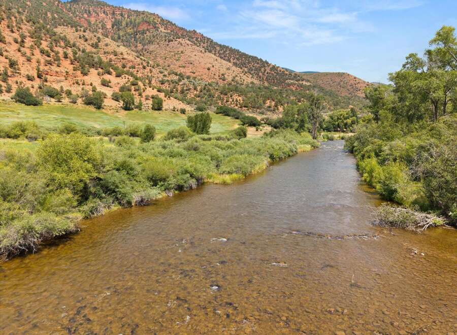 Experience the tranquility of this stunning property, featuring a picturesque river flowing through lush greenery and against a backdrop of majestic red rock mountains.