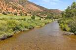 Experience the tranquility of this stunning property, featuring a picturesque river flowing through lush greenery and against a backdrop of majestic red rock mountains.