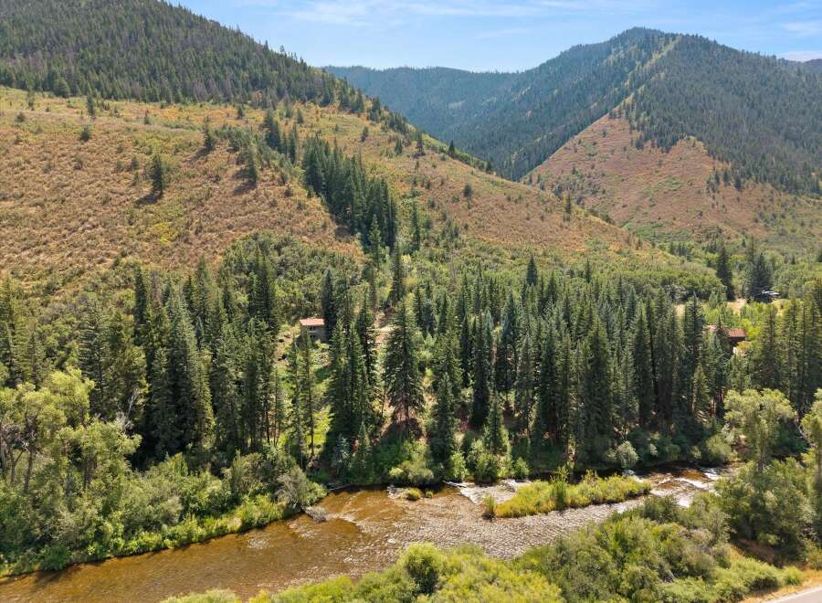 Escape to this secluded mountain retreat, nestled beside a pristine river and surrounded by lush evergreen forests.