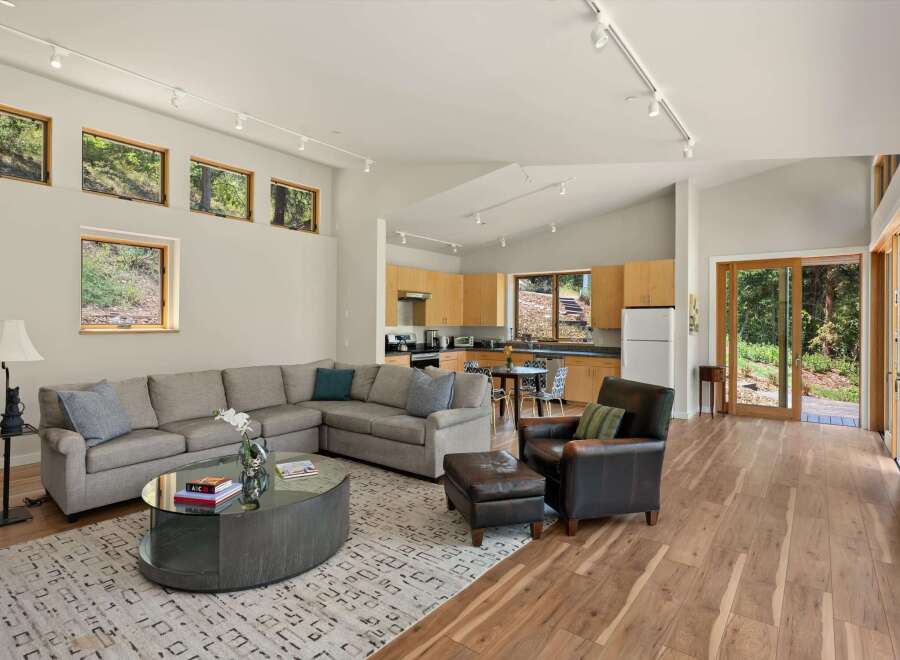 Experience seamless indoor-outdoor living in this stunning open-concept home, featuring a spacious living area with a large sectional sofa and a modern coffee table.