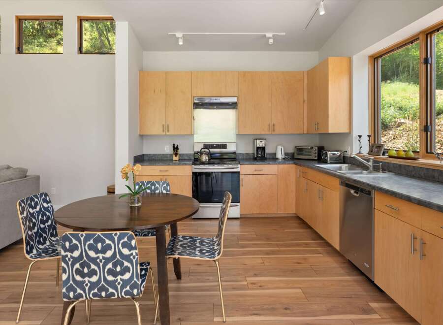 This modern kitchen features light wood cabinetry and sleek countertops, complemented by a stainless steel range and dishwasher.