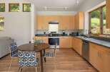 This modern kitchen features light wood cabinetry and sleek countertops, complemented by a stainless steel range and dishwasher.