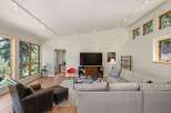 Experience modern living in this stunning living room, featuring a vaulted ceiling with track lighting and expansive windows that flood the space with natural light.