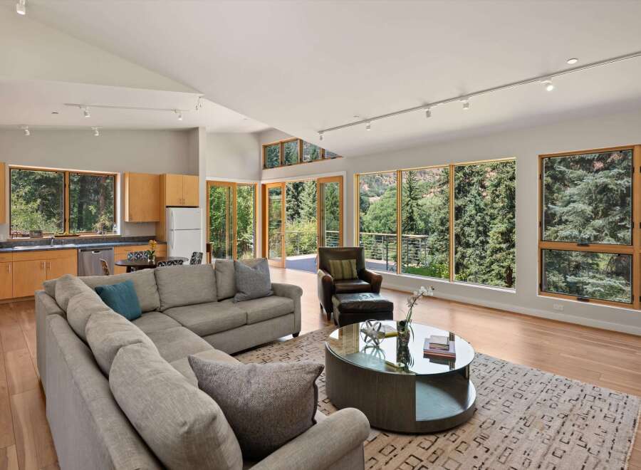 Experience breathtaking mountain views from this stunning modern living space, featuring a spacious sectional sofa and a sleek glass-top coffee table.