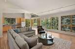 Experience breathtaking mountain views from this stunning modern living space, featuring a spacious sectional sofa and a sleek glass-top coffee table.