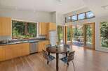 Experience seamless indoor-outdoor living in this stunning kitchen and dining area, featuring expansive windows and glass doors that open to a scenic deck with mountain views.