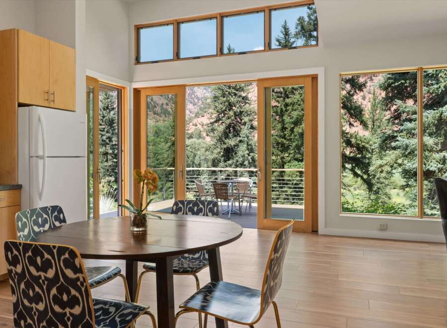 Experience breathtaking mountain views from this stunning dining area, featuring a round wooden table and chairs with a unique patterned upholstery.