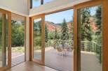 Experience seamless indoor-outdoor living with expansive sliding glass doors that open onto a spacious deck, offering breathtaking views of the surrounding red rock mountains and lush greenery.