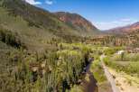 Nestled in a picturesque mountain valley, this property offers a serene retreat with a winding river and lush greenery.