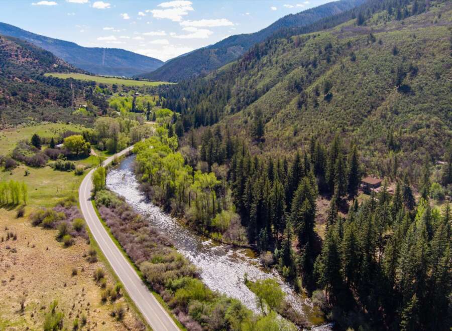 Nestled amidst a lush, mountainous landscape, this property offers a serene retreat with a winding river and a scenic road.