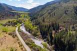 Nestled amidst a lush, mountainous landscape, this property offers a serene retreat with a winding river and a scenic road.